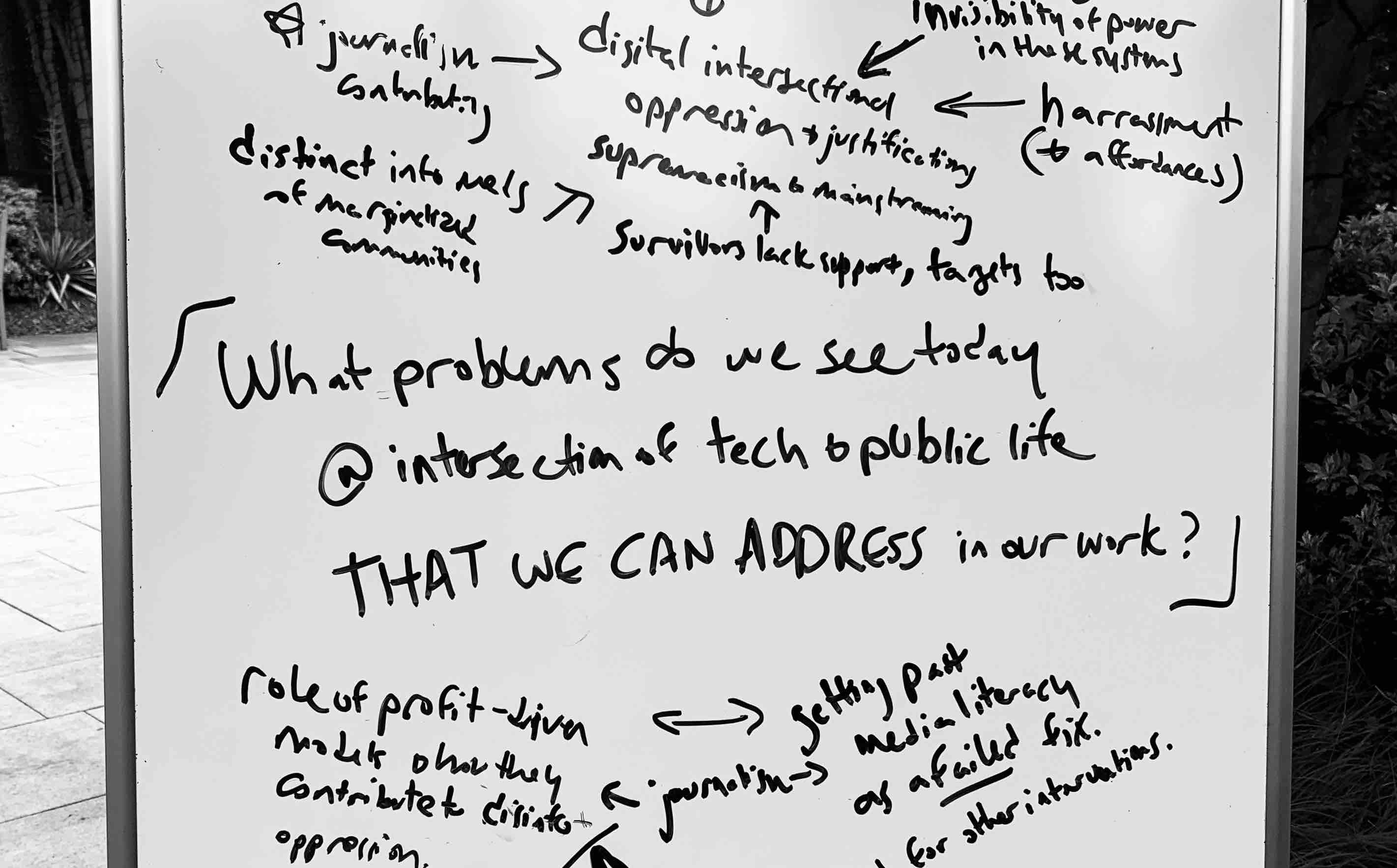 photo of a whiteboard from a strategy conversation on the topic of 'What problems do we see today @ intersection of tech & public life THAT WE CAN ADDRESS in our work?' Responses include 'invisibility of power in these systems' and 'distinct info needs of marginalized communities.'